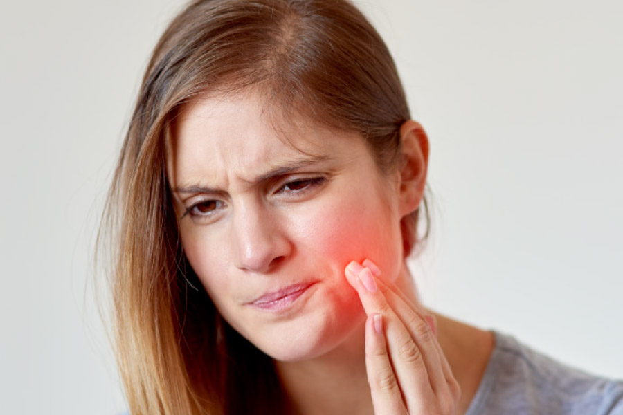 Girl with her hand to cheek which is radiating red to indicate tooth pain