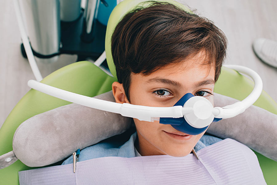 Photo of a boy in the dental chair receiving nitrous oxide sedation through a nose piece.