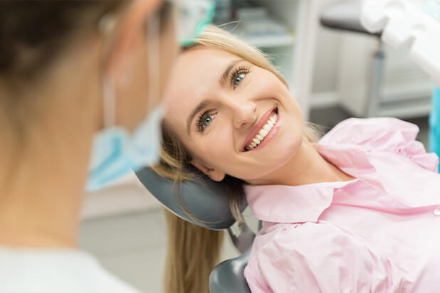 woman with a bright, white smile speaking with her dentist