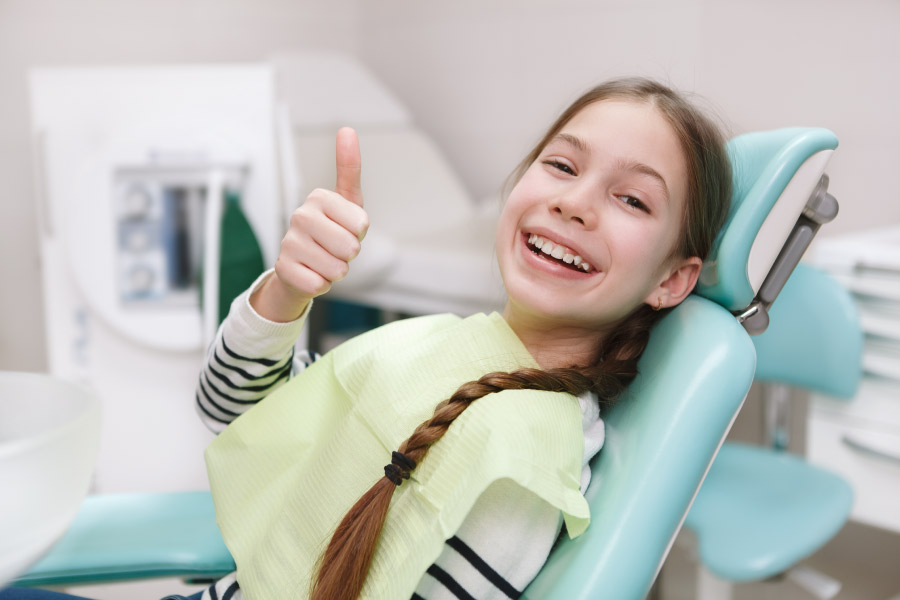 Young teen with braids giving a thumbs up sign from the dental chair.