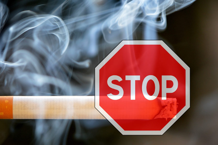Stop sign in front of a smoldering cigarette.