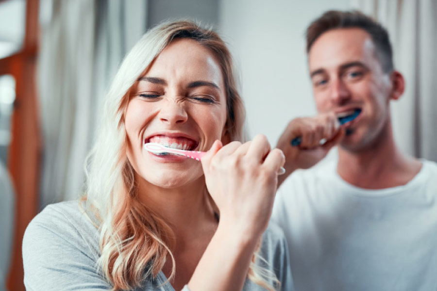 A couple brushing their teeth in front of the mirror before bed.