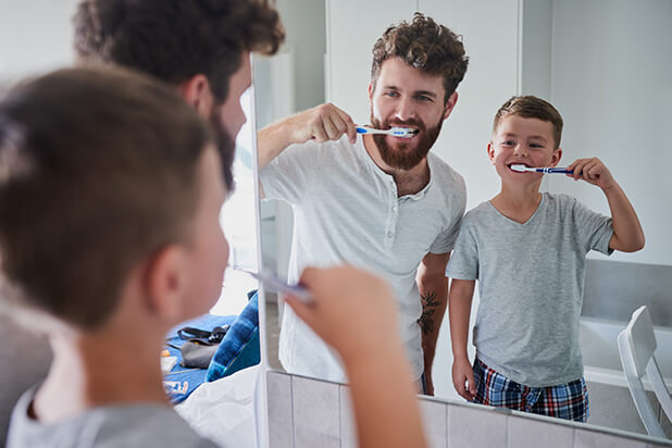 father and son brushing their teeth together