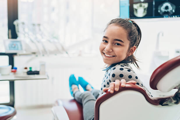 young, smiling girl sitting in a dental chair