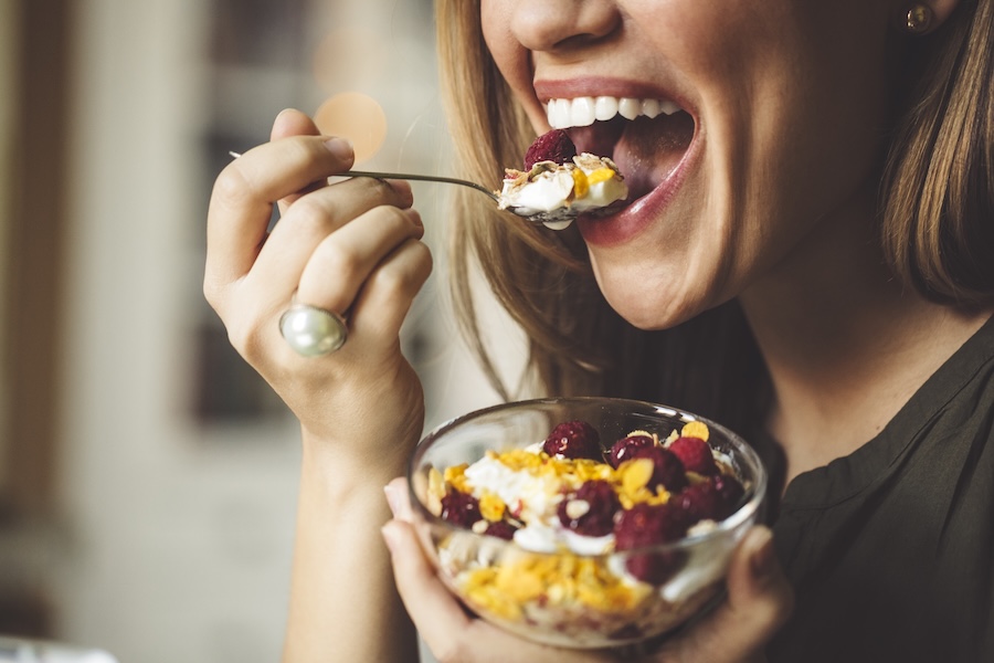 woman eating berries and yogurt, healthy foods for gum health to prevent gum disease