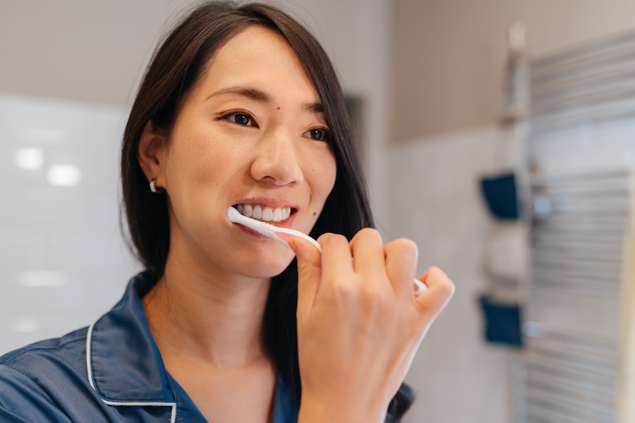 woman brushing her teeth to extend the life of her composite fillings, composite filling care