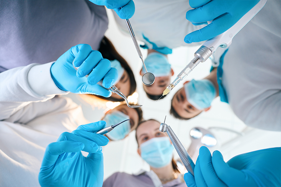 Upward looking at masked faces of technicians holding tools used for oral surgery