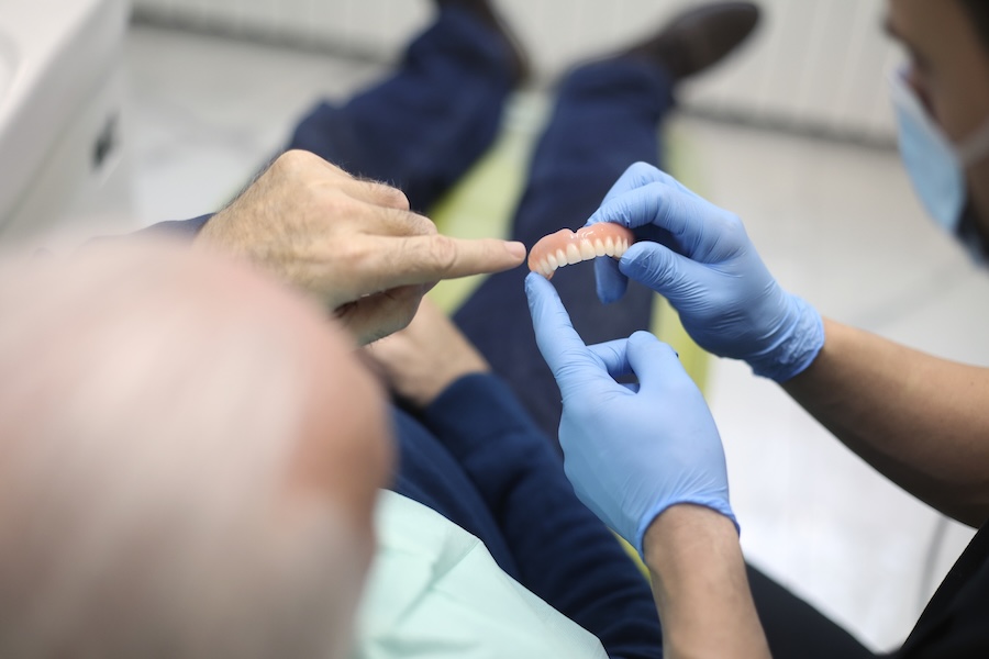 man talking about dentures with the dentist, signs dentures need to be replaced